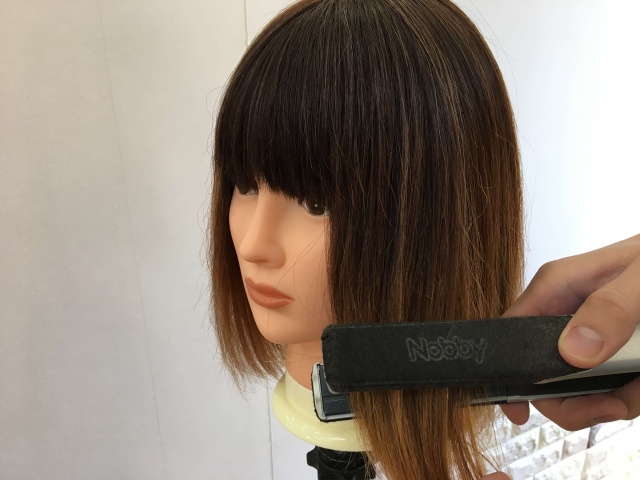 ストレートアイロンで挟んで毛先から抜いている写真