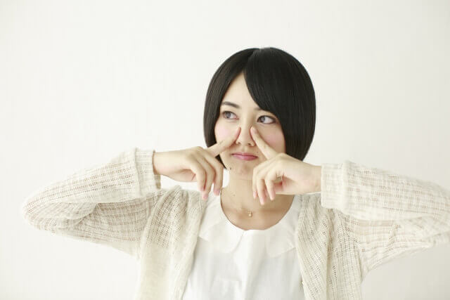鼻をつまむ女性の写真