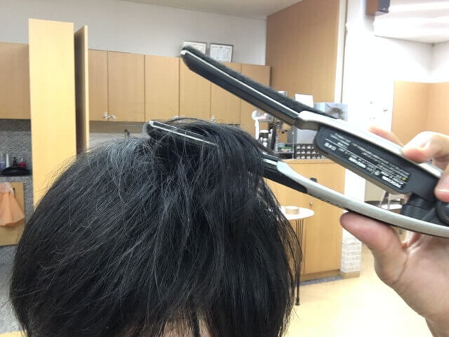 ストレートアイロンで髪の毛をはさむところの写真