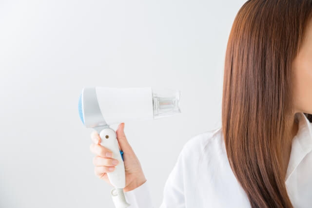 ドライヤーを使っている女性の写真