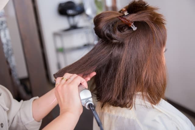 ヘアアイロンで施術している美容師