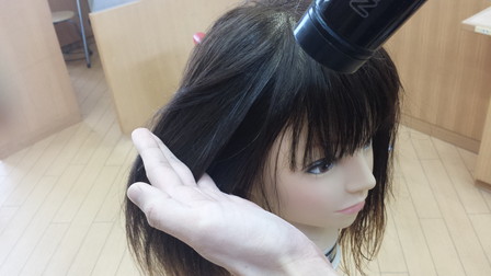 指で梳かしながらドライヤーで乾かしている写真