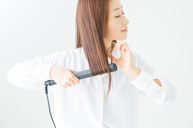 ストレートアイロンを使う女性の写真