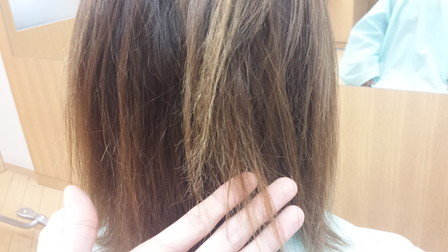 泡カラーでダメージしてしまった人の髪の毛を手で触っている