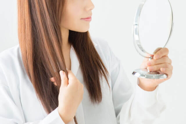 髪の毛をチェックする女性の写真