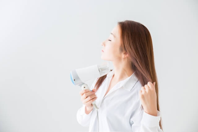 ドライヤーで髪の毛を乾かす女性の写真