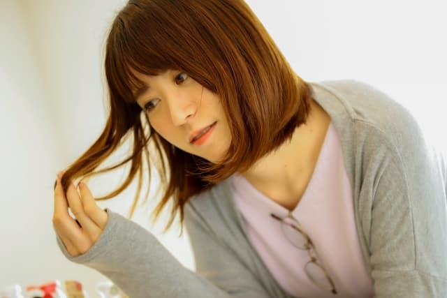 傷んだ髪を見ている女性