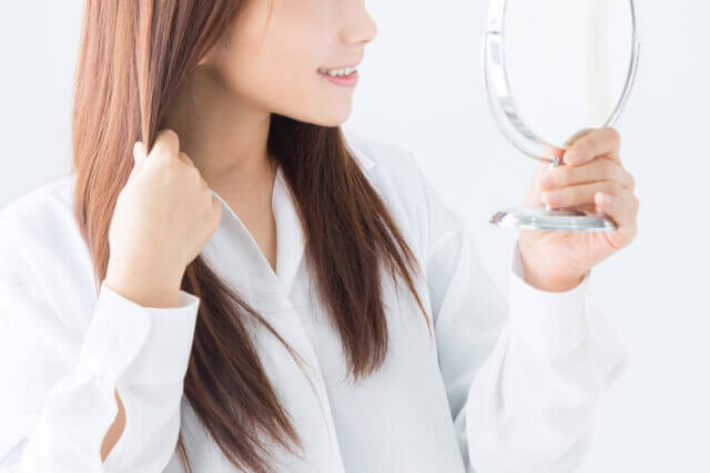 髪をチェックする女性の写真
