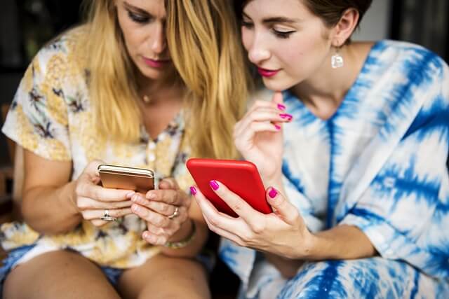 スマートフォンをチェックする2人の女性の写真