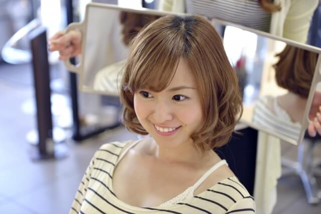 髪型の仕上がりのチェックする女性の写真