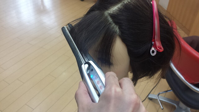 ストレートアイロンで前髪を巻いている写真