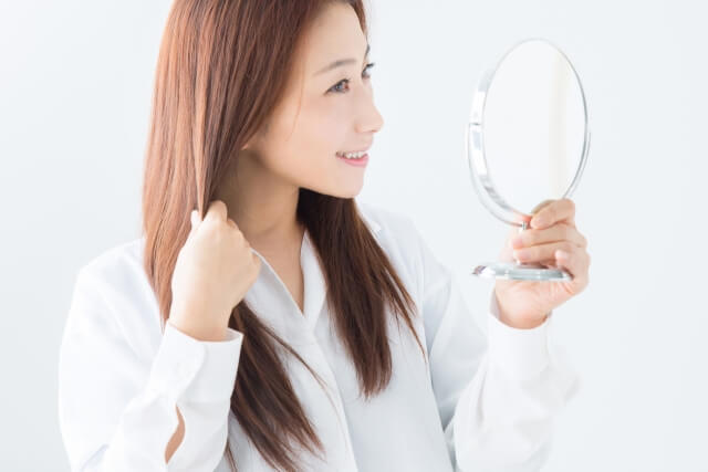 鏡で髪を見る女性