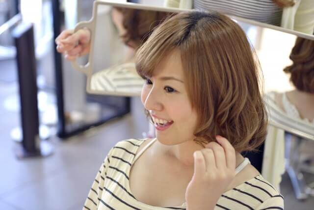 髪型の仕上がりを確認する女性の写真